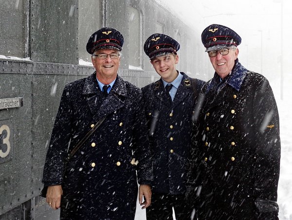 Drei gut gelaunte Zugbegleiter im Schneetreiben